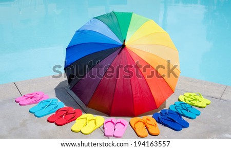 Color umbrella and flip flops by the swimming pool in sunny day