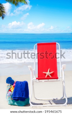 Beach chair with starfish and bag on the sandy beach by the ocean