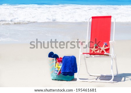 Beach chair with starfishes and bag on the sandy beach by the ocean