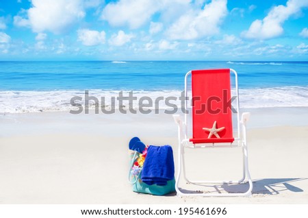Beach chair with starfish and bag on the sandy beach by the ocean