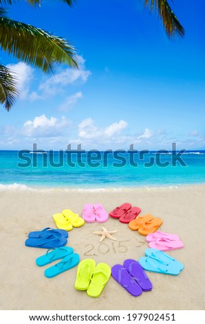 Number 2015 with color flip flops and starfish on the sandy beach - new year concept