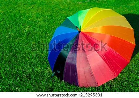 Rainbow umbrella on the green grass in sunny day