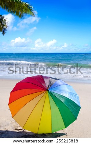 Rainbow umbrella by the ocean in sunny day