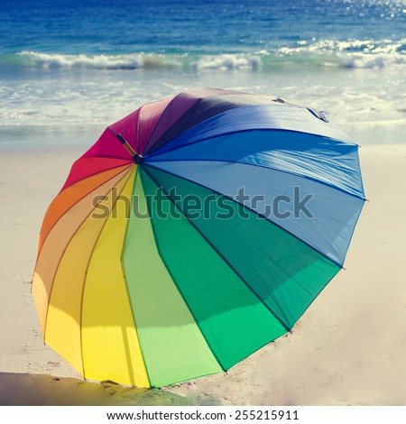 Rainbow umbrella by the ocean in sunny day (instagram effect)
