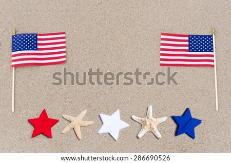 American flags with white, blue and red stars and starfishes on the sandy beach - USA holidays concept