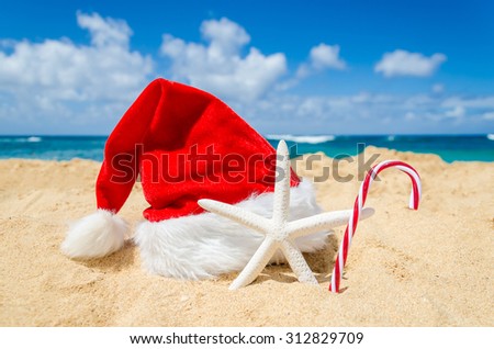 Merry Christmas and Happy New Year background with Santa Claus Hat, candy and starfish on the tropical beach near ocean in Hawaii