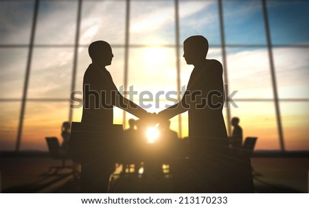 Two business shake hand in office silhouettes
