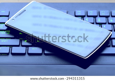 Smart Phone On Computer Keyboard With Green Keys