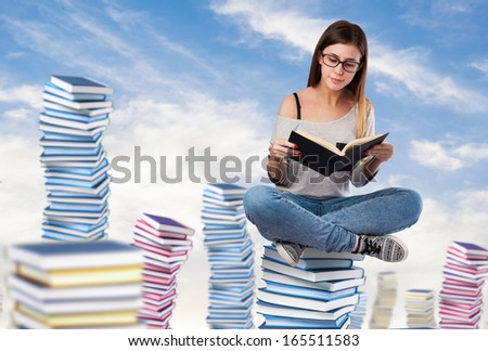 young woman reading a book sitting on a books pile on the sky