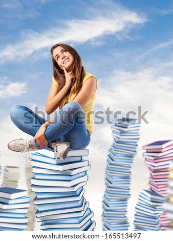 young pretty woman thinking and sitting on a big books pile