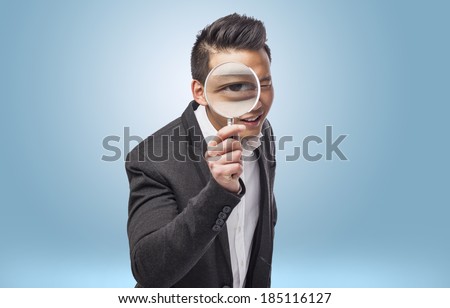 young asian business man looking through a magnifying glass