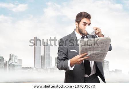 handsome young business man drinking and reading a newspaper