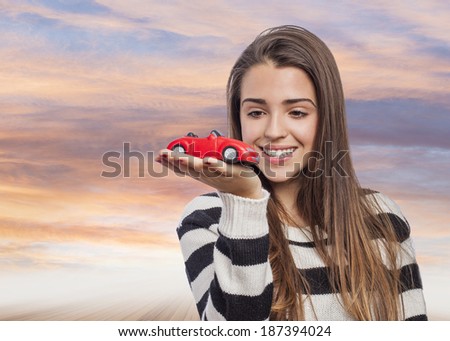 Beautiful young woman holding a red car