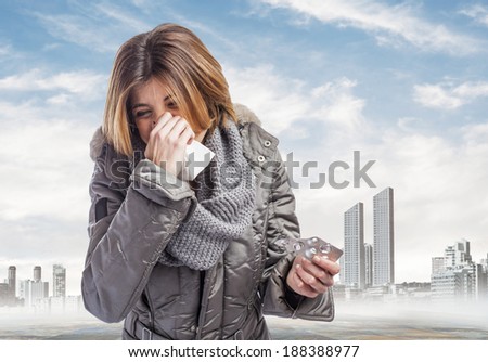 beautiful young woman sneezing and holding medicines