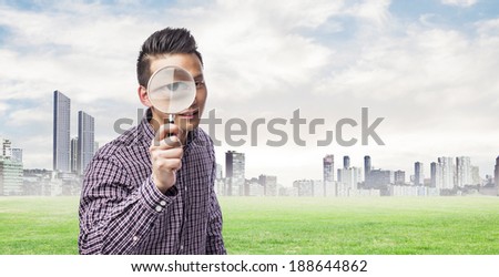 handsome young asian man looking through a magnifying glass