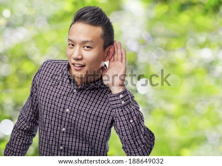 Handsome young asian man trying to hear something