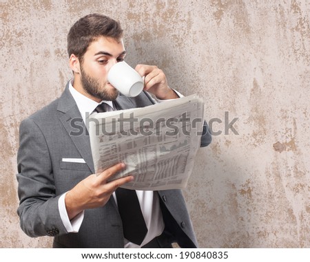 handsome young business man drinking and reading a newspaper