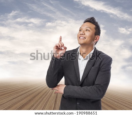 handsome young asian man pointing up with finger