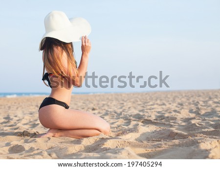 girl sitting on the beach looking at the horizon