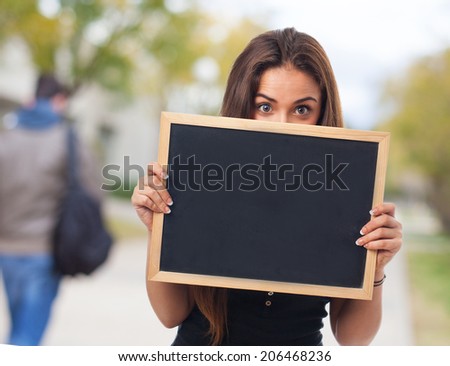 portrait of a young student hidden behind a chalkboard