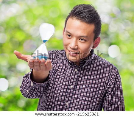 handsome young asian man holding a sand timer at park