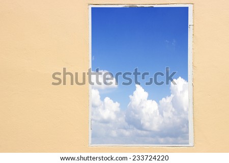 View from the old window - wooden frame of sky and cloud; view through the window wooden frame on the wall background. window wooden frame in the sky, window against a wall the sky and cloud