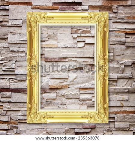 Antique frame on stone wall background ,gold picture frame on sandstone Brick Wall Surfaced background ; Blank photo frame on sandstone.  Empty picture frame on sandstone wall.