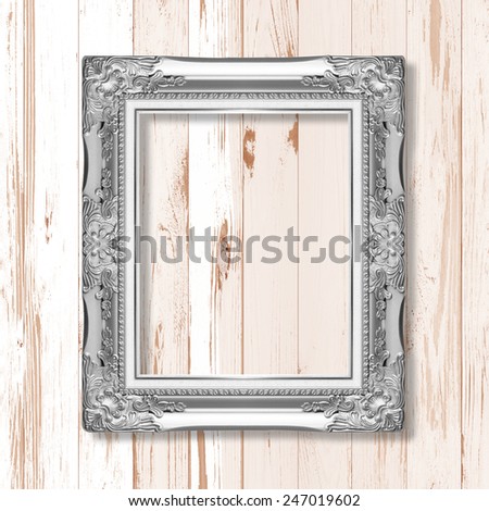 silver picture frame on wooden wall;. Empty  picture frame on wooden wall.