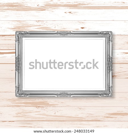 silver picture frame on wooden wall;. Empty  picture frame on wooden wall.