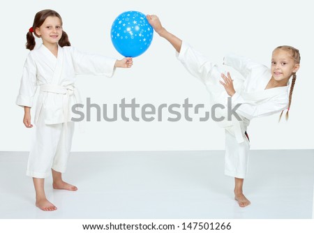 Two little girls with blue ball beat a karate kick leg