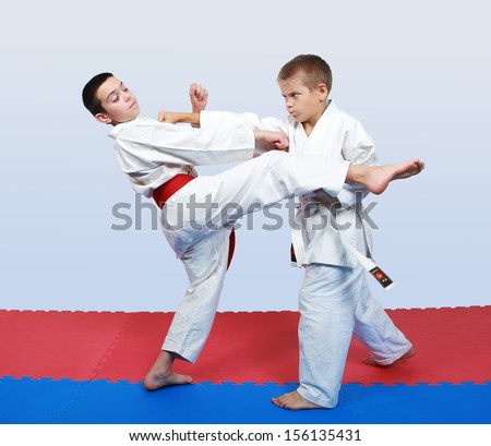 An athlete with a white belt beat a punch in response to kick an athlete with a red belt