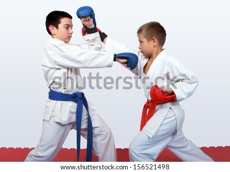 With a red and a blue belt athletes doing paired exercises  karate
