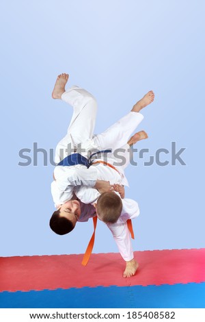 On a light background athletes is doing judo throws