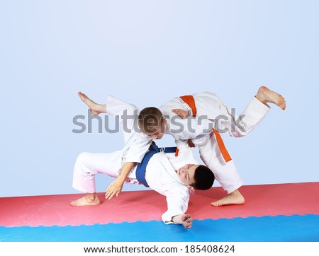 Sportsman with an orange belt threw athlete with a blue belt
