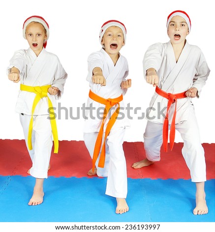 Three children with different belts punching by fist in the air and shout ki-ai