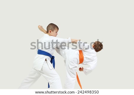 On a gray background two sportsmen are doing paired exercises karate