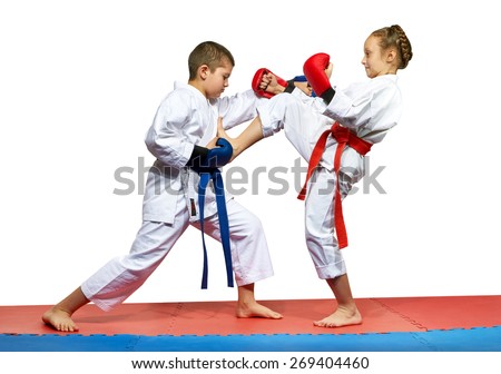 The girl with a red belt kicks the boy with a blue belt