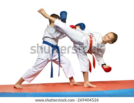 The girl with a red belt kicks the boy with a blue belt