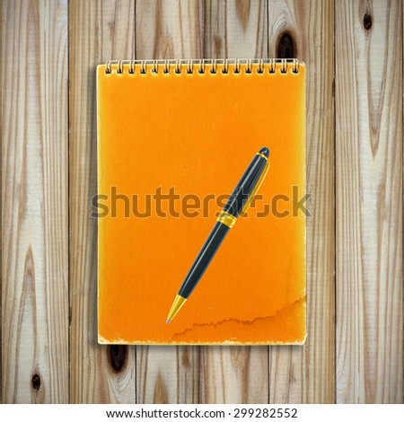 Notebook and pen isolated on wooden background