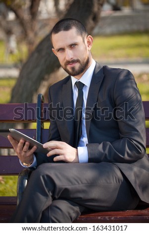 Businessman working on his pc tablet outdoors