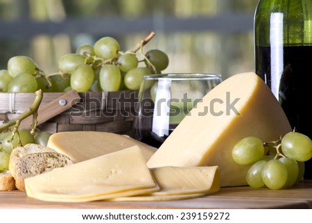 Wine bottle with a glass of red wine with cheese and grapes