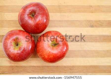 red apple sit on a worn butcher block cutting board