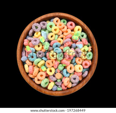 Delicious and nutritious fruit cereal loops flavorful in wooden bowl on black background