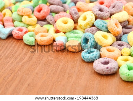 Delicious and nutritious fruit cereal loops flavorful on wooden board, healthy and funny addition to kids breakfast