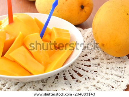 Mango slice isolated in white plate on wooden board