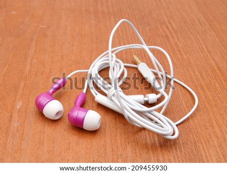 Pink and white earphones on wooden board