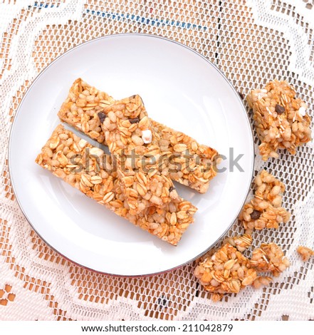 Granola bars with chocolate in white plate on wooden board