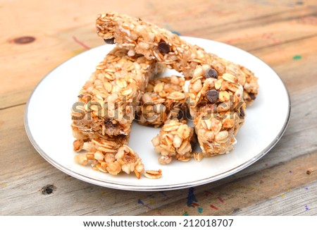 Granola bars with chocolate in white plate on wooden board