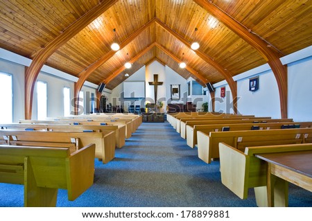 The interior of a simple church with a vaulted wooden ceiling and beams