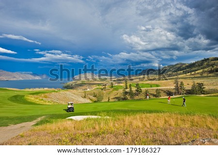 The rolling hills of a beautiful golf course and the green fairways in the sun with clouds dappling the blue sky